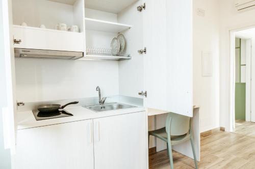 a white kitchen with a sink and a chair at Silvia's Luxury Suites by RentMax in Canegrate
