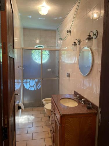 a bathroom with a shower and a sink and a toilet at Memora Guesthouse Bateias - Casa Inteira ou quartos em chácara in Campo Largo