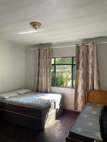 a bedroom with a bed and a window at Memora Guesthouse Bateias - Casa Inteira ou quartos em chácara in Campo Largo