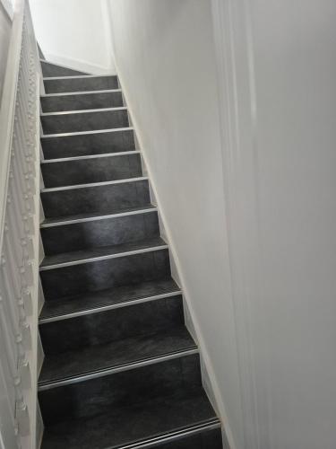 a staircase with black treads and white walls at One bed flat in UB5 in Northolt