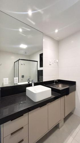 a bathroom with a sink and a large mirror at Studio Amplo e Aconchegante com 2 Camas in Campo Grande