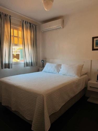 a bedroom with a large white bed with a window at Condo-Resort Juquehy, 4 quartos, em frente ao mar in São Sebastião