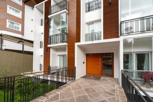 an apartment building with a walkway in a courtyard at Stay Home Luxo Gramado - 1 min da rua Coberta - Tudo a pé - Apartamentos Decorados - Varanda - Ar condicionado quente e frio - Roupas de cama Premium in Gramado