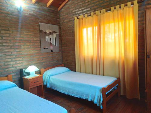 a bedroom with two beds and a window with yellow curtains at Cabañas Llajta Sumaj in Las Calles