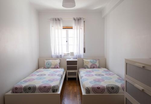 two beds in a small room with a window at Baleal Holiday House in Baleal