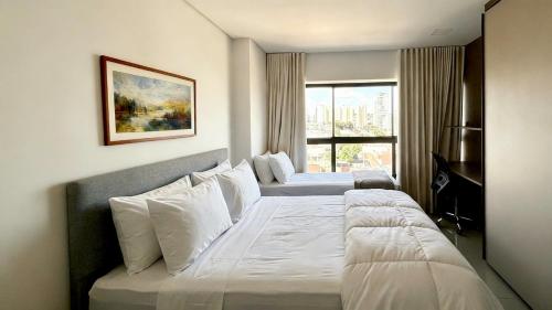 a hotel room with two beds and a window at Studio Amplo e Aconchegante com 2 Camas in Campo Grande
