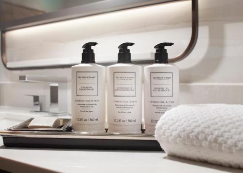 a group of three bottles of moisturizers on a bathroom counter at Hilton Anatole in Dallas