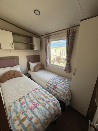 a small bedroom with two beds and a window at Oakley caravan rental in Skegness