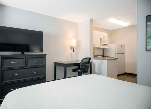 a bedroom with a bed and a desk and a refrigerator at Extended Stay America Suites - Portland - Scarborough in Scarborough