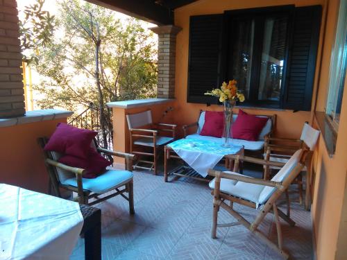 eine Veranda mit Stühlen und einem Tisch mit einer Blumenvase in der Unterkunft Villa Donna Maria in Capoterra