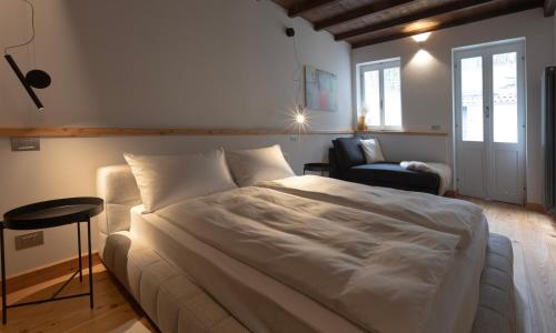 a bedroom with a large white bed and a chair at La casa del lupo in Colico