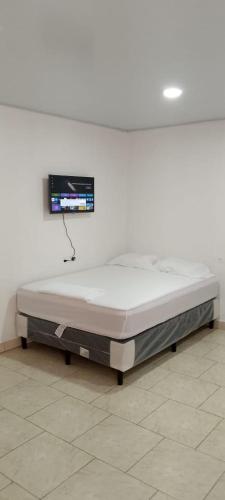 a bed in a room with a tv on the wall at Apartamento INRU in Puerto Cortés