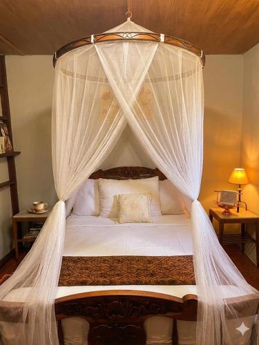 a bedroom with a canopy bed with white curtains at Refugio El Dormilón, Jardín cercado, Wifi, Playa 300 m, Pet friendly in La Pedrera