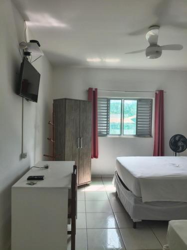 a bedroom with a bed and a desk and a television at Pousada Esperança - Areias SP in Areias
