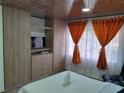 a bedroom with a bed and a tv and curtains at Alojamiento y Confort in Tunja
