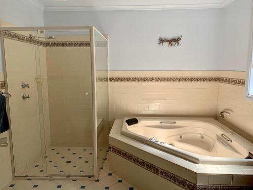 a bath tub in a bathroom with a shower and a tub at Bay-Ann Cottage in Kingscote