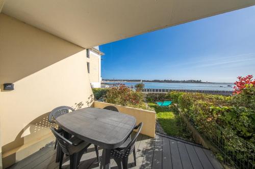 a table and chairs on a balcony with a view of the ocean at Sea-view garden-level flat in Ploemeur