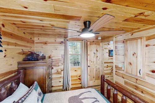 a log cabin bedroom with a bed and a ceiling fan at Meandering Moose Cabin in Florissant