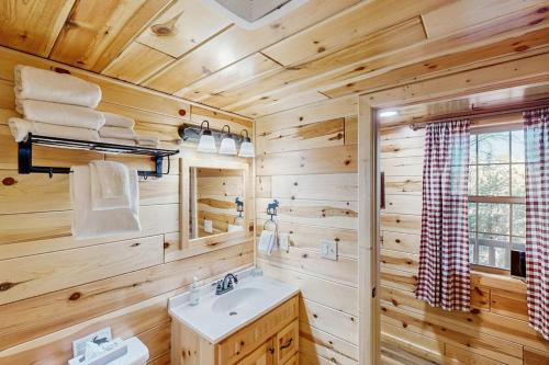 a bathroom with wooden walls and a sink and a window at Meandering Moose Cabin in Florissant