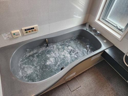 a bath tub filled with water in a bathroom at Takayama Fortune-inn in Takayama