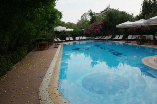 a large blue swimming pool with chairs and umbrellas at Mr. Dim Exclusive Apart Hotel in Göcek