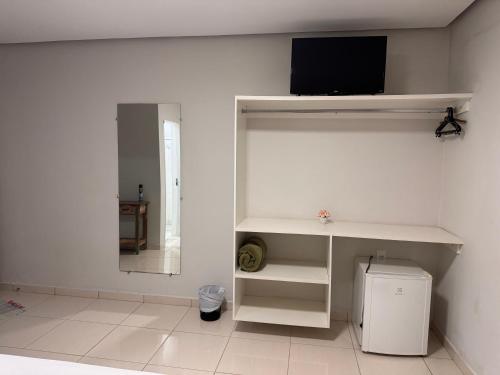 a white room with a tv on a wall at Pousada Xero in Capitólio