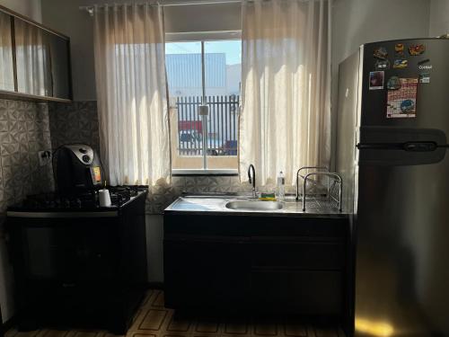 a kitchen with a sink and a refrigerator and a window at La casita in Foz do Iguaçu