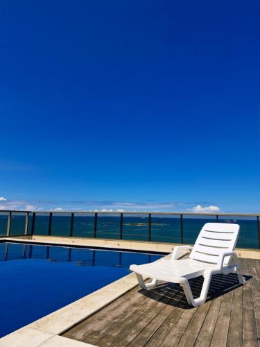 a white chair sitting on a deck next to a pool at Praia Dourada SUÍTE ITAPARICA 1206 in Vila Velha