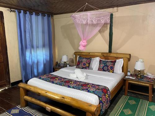 a bedroom with a bed with a wooden headboard and blue curtains at Ruhondeza Lodge in Buhoma