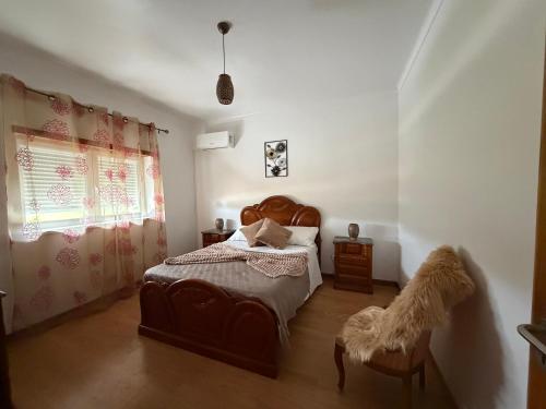 a bedroom with a bed and a chair and a window at Casa da Tininha in Alcobaça