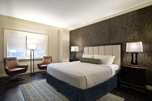 a bedroom with a large bed and two chairs at The Whitehall Houston in Houston