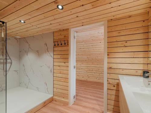 a bathroom with wooden walls and a shower and a sink at ZweveZalig in Zwevezele