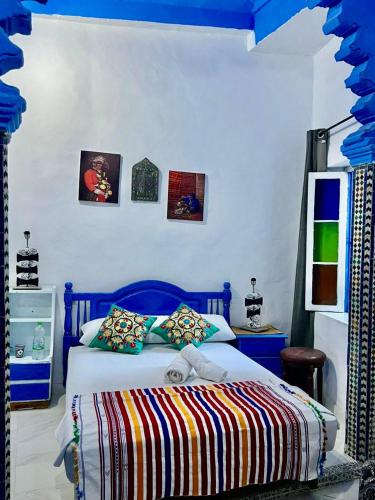 a bedroom with a bed with a blue head board at maison bleu hajja in Tangier