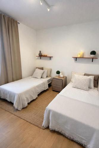 two beds in a room with white walls at CASA DEL MAR-Costa Daurada in Cunit