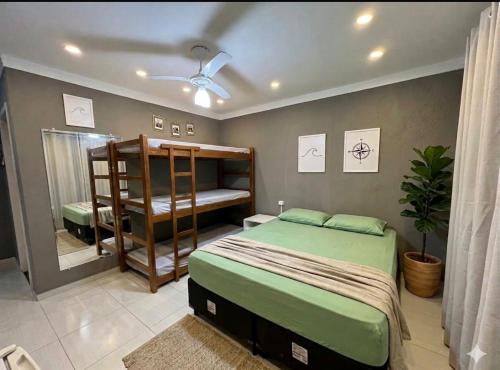 a bedroom with a bed and a bunk bed and a window at Moriah Hostel e Pousada in Praia Grande