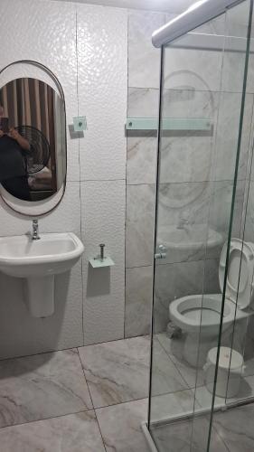 a bathroom with a sink and a mirror and a toilet at Cananéia Apoio Tours in Cananéia
