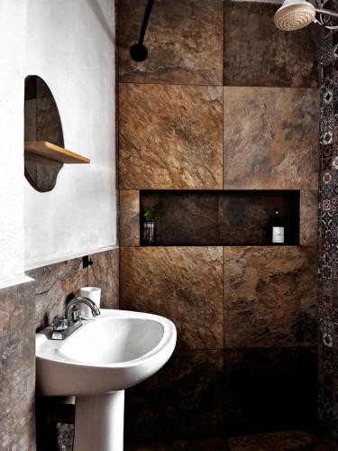 a bathroom with a white sink and a brown wall at Casa Roma in Taxco de Alarcón