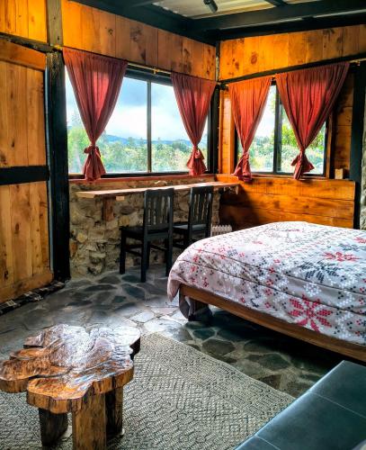 a bedroom with a bed and a table and windows at Chalet Stonehenge in Pasto