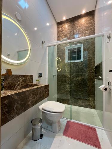 a bathroom with a toilet and a glass shower at Laranjeiras House in Uberaba