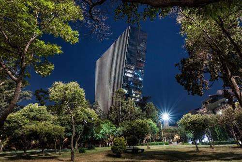 a tall skyscraper in a park at night at Alexander, Member of The Leading Hotels of the World in Mexico City