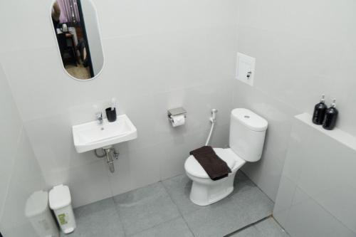 a white bathroom with a toilet and a sink at Escotel Majestica in Dalung