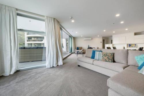 a living room with a couch and a large window at Oceanside Apartment with Pool Views in Mount Maunganui
