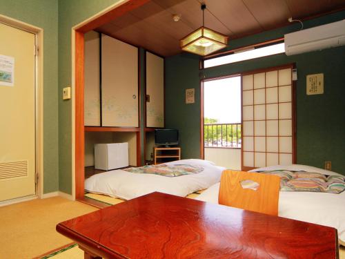 a room with two beds and a table and a window at Hotel Sankyu in Tsukuba
