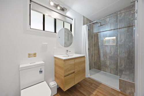 a bathroom with a shower and a toilet and a sink at Agnes Bush Cabins in Agnes Water