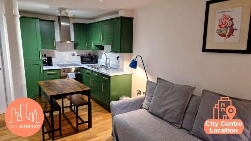 a living room with a couch and a kitchen with green cabinets at Northern Quarter Flat in Manchester
