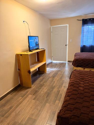 a room with two beds and a desk with a television at HOTEL Y CABAÑAS El PINO in Creel