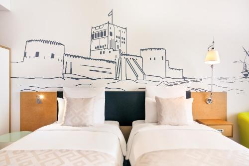 two beds in a room with a drawing on the wall at Mercure Sohar in Sohar