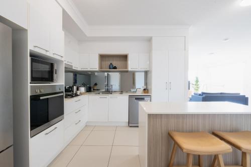 a kitchen with white cabinets and a counter with stools at Boulevard North Lakes in North Lakes