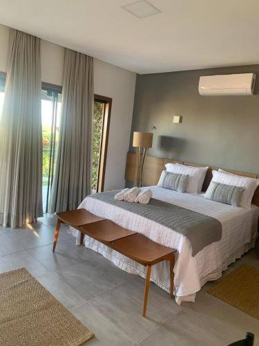 a bedroom with a large bed and a large window at Chalé Village da Serra in Serra de São Bento