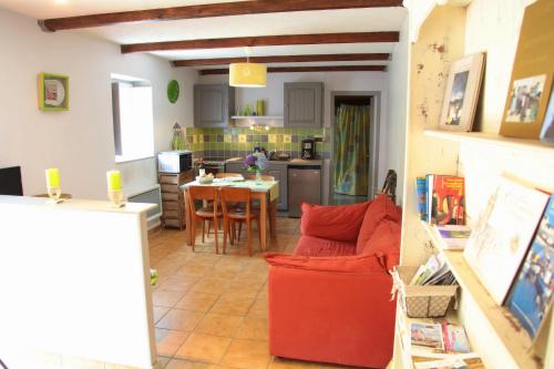 eine Küche mit einem roten Sofa und einem Tisch in der Unterkunft Moulin De Beuzidou in Saint-Urbain
